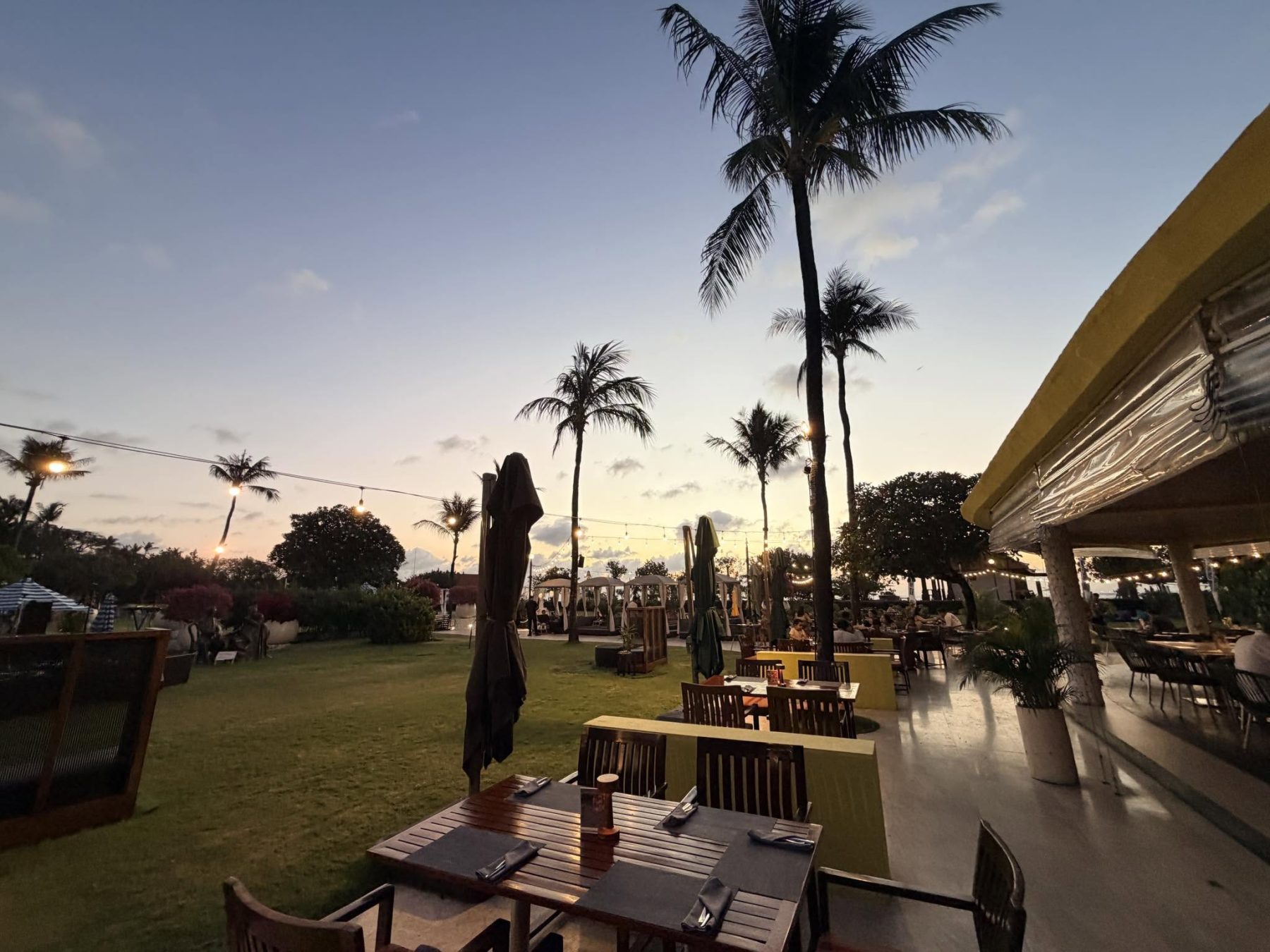 峇里島 Holiday Inn Baruna ENVY 暮色木桌與草坪串燈