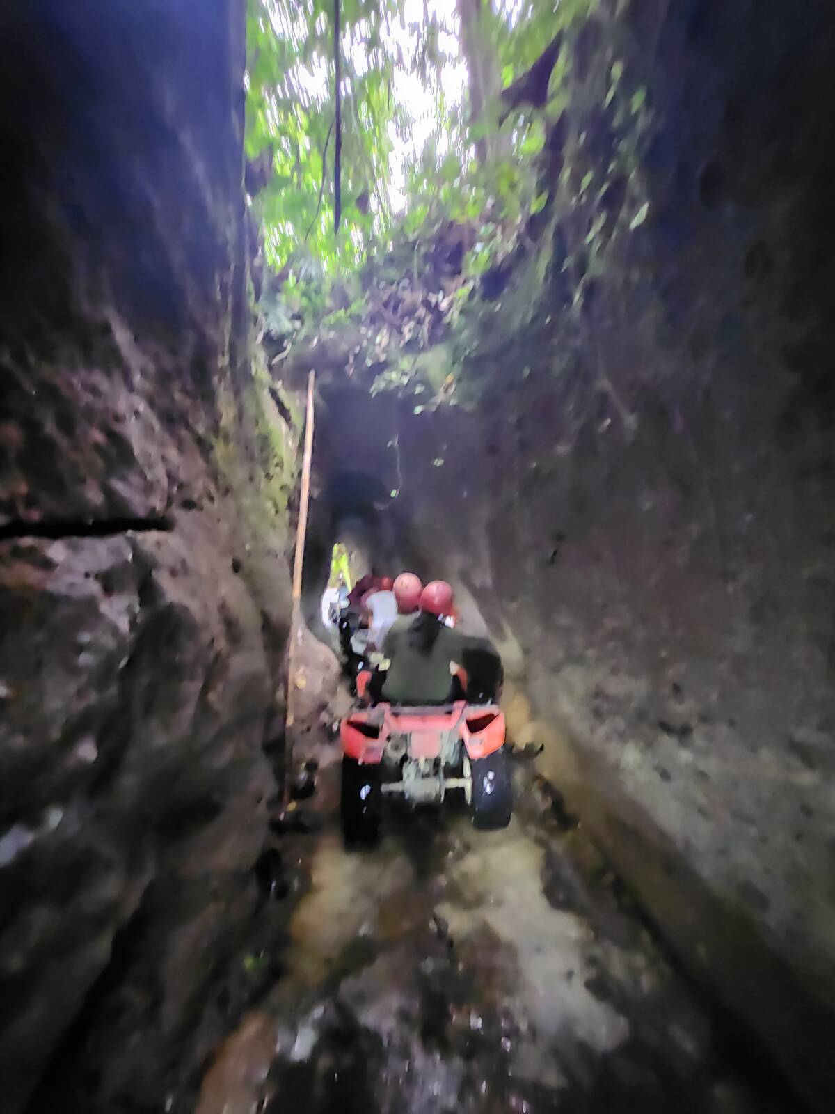ATV 車隊從光線昏暗的天然岩壁狹窄水道中穿過