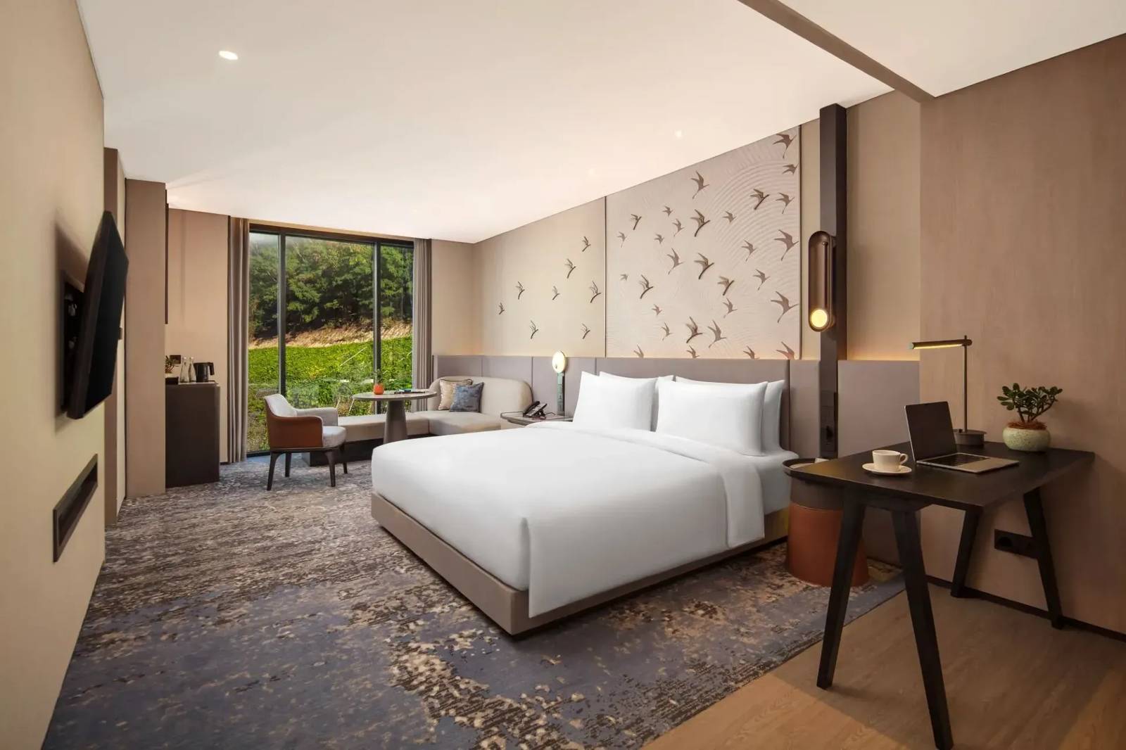 Crowne Plaza Labuan Bajo 客房大床、書桌與窗邊沙發座位