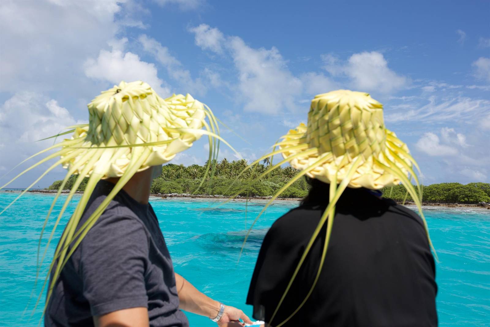 提克豪環礁潟湖上戴著椰葉帽的旅客