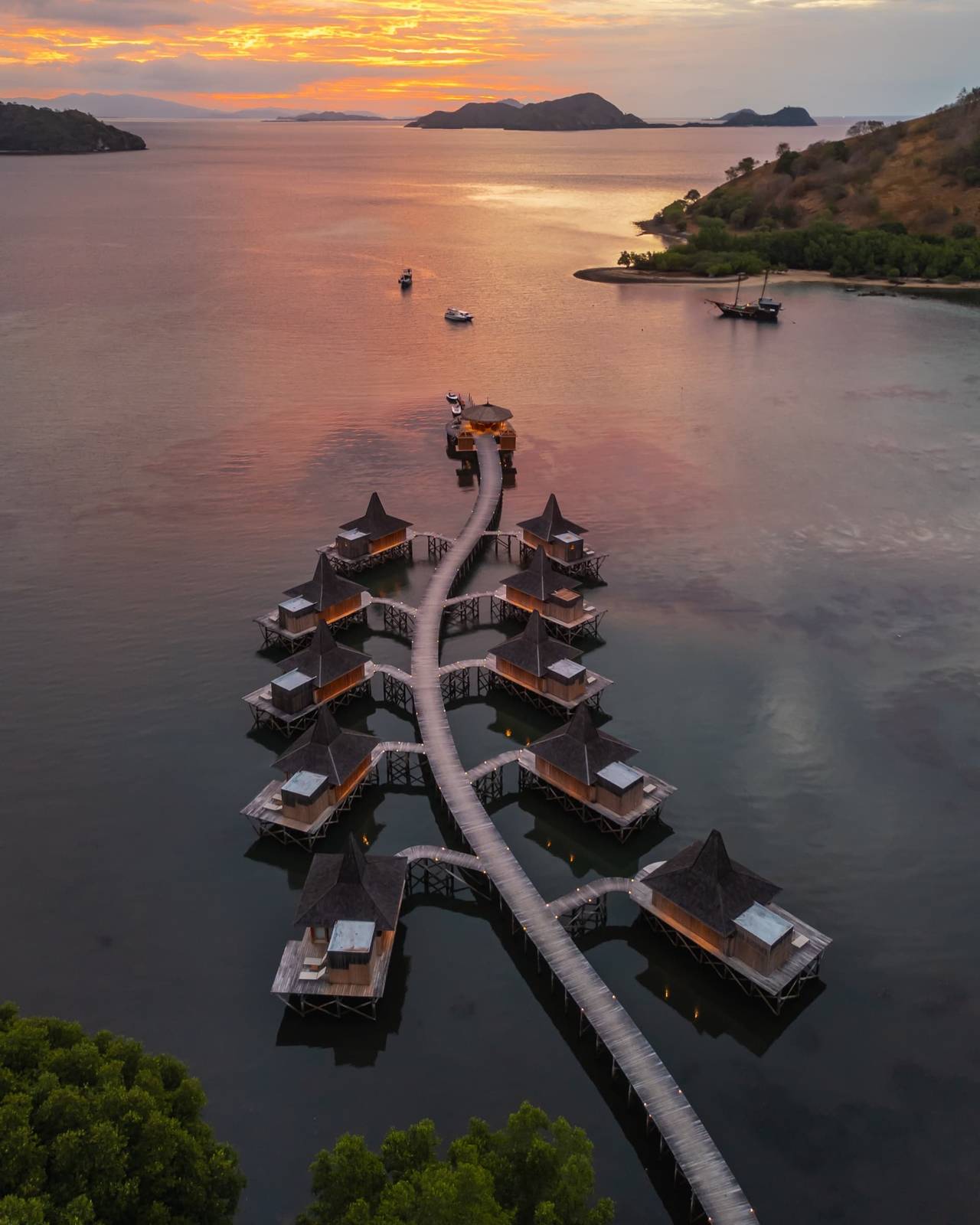 Menjaga Bay 黃昏空拍長棧橋與成對尖頂水上小屋、末端圓亭與白船