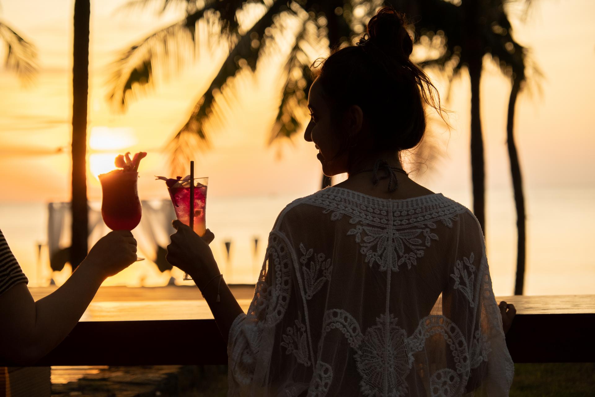 日落時海邊舉杯的旅客