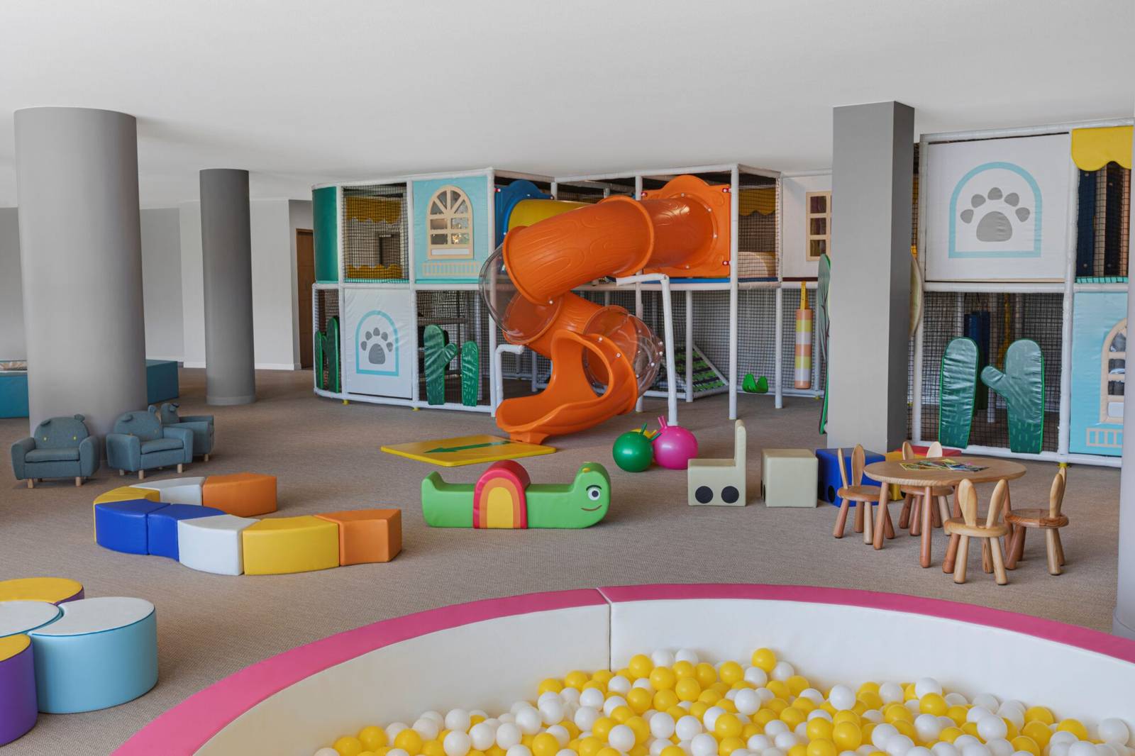 金蘭 Alma 度假村 Kids Club 室內遊戲室:橘色螺旋滑梯、黃白球池與地毯上的軟墊玩具