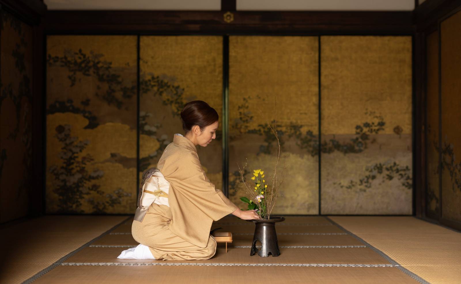和室中身著和服者正在整理花器