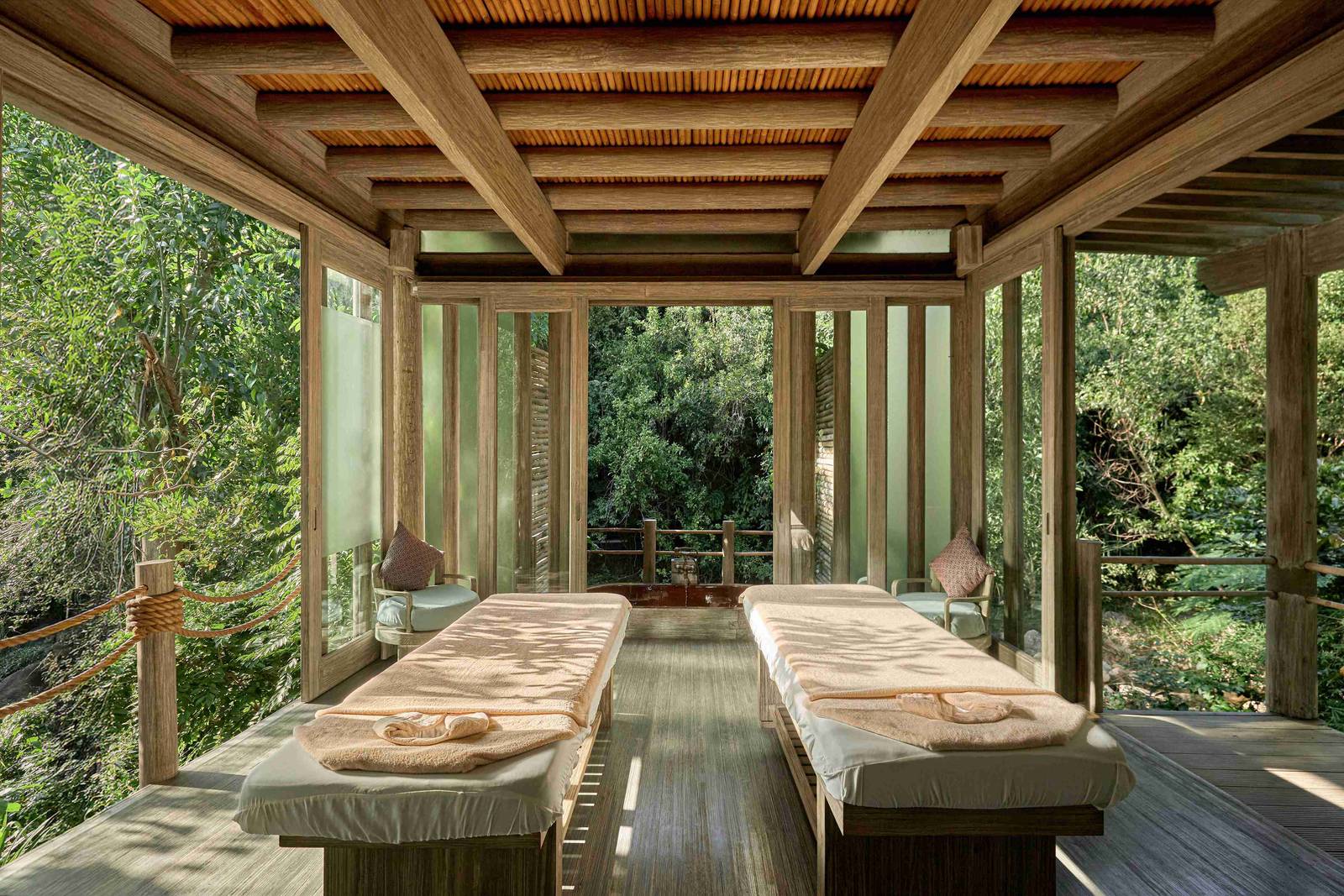 寧凡灣安嵐 Jungle Spa:兩張鋪白巾的按摩床面對落地窗與叢林,後方可見木作浴槽