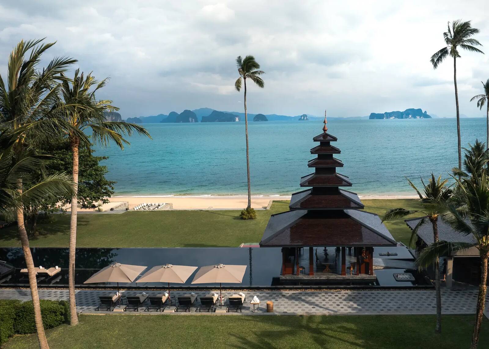 ÀNI Thailand 主泳池與多層涼亭前方的沙灘，遠處是攀牙灣石灰岩島