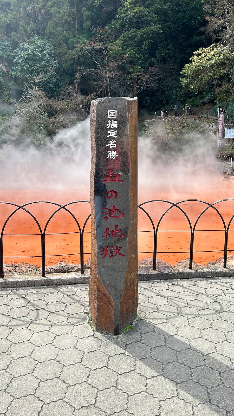 血之池地獄名勝標柱後方是紅色熱泥泉與升起的湯煙