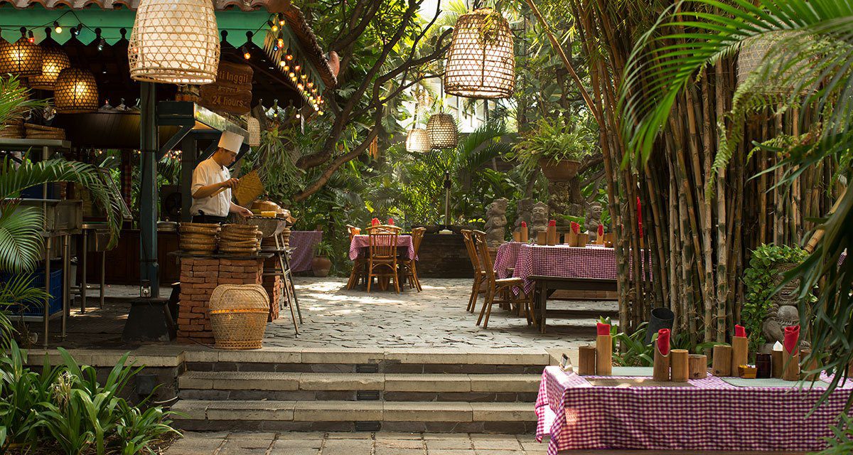 Pasar 庭園市集的用餐長桌與藤編吊燈，四周是熱帶植栽與石階