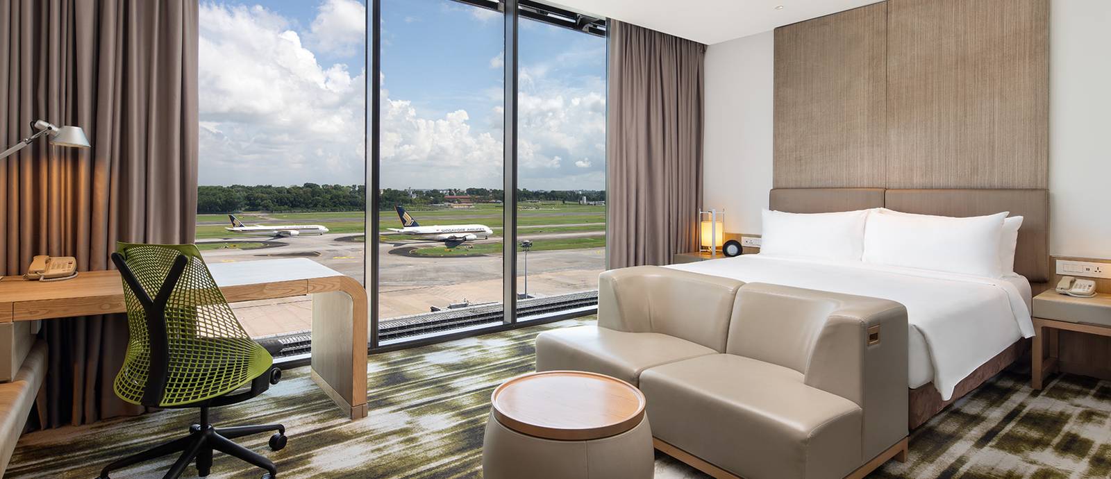 Crowne Plaza Changi Airport 客房大床、沙發與窗外停機坪上的飛機