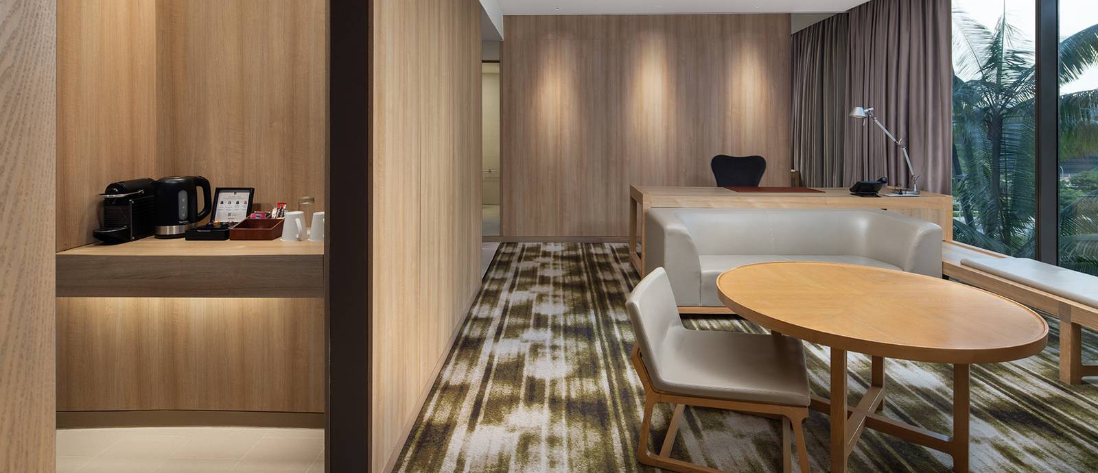Crowne Plaza Changi Airport 套房客廳的圓桌、工作桌與窗邊綠意