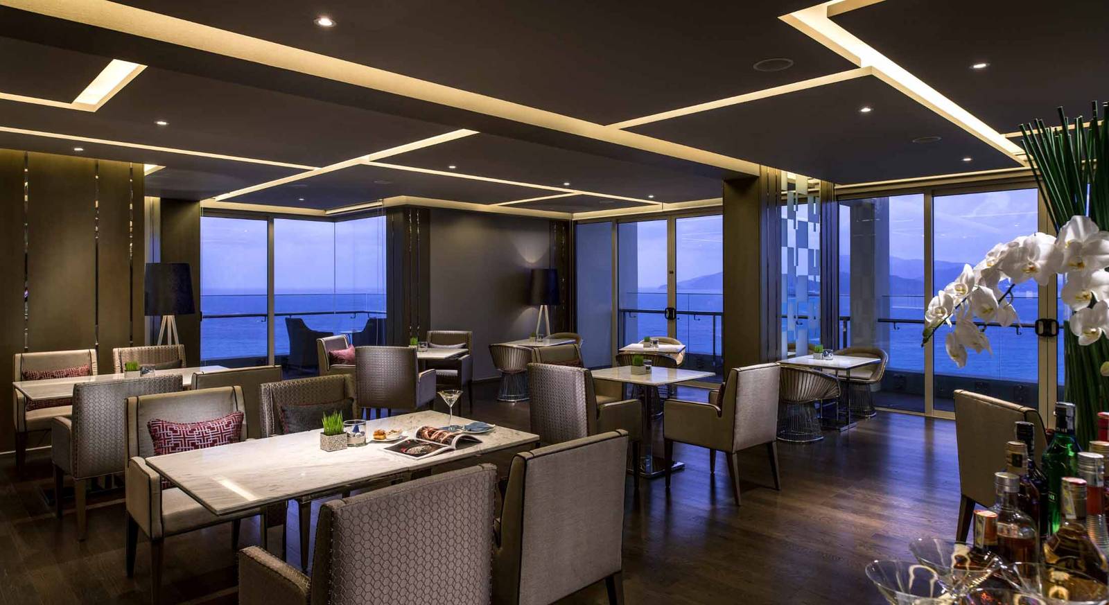 芽莊洲際酒店 Club Lounge 黃昏時分，大理石桌與高背椅面向落地窗外的芽莊灣