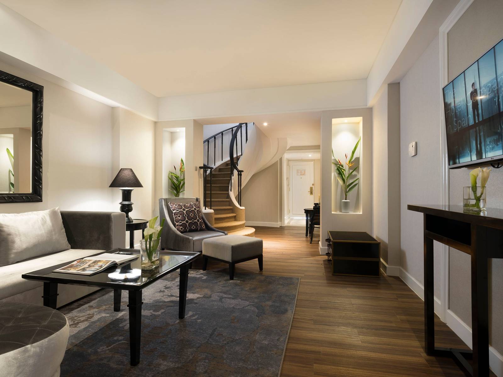 日惹美利亞普羅薩尼酒店 Junior Suite 客廳：沙發與扶手椅，後方是弧形樓梯與鐵欄杆