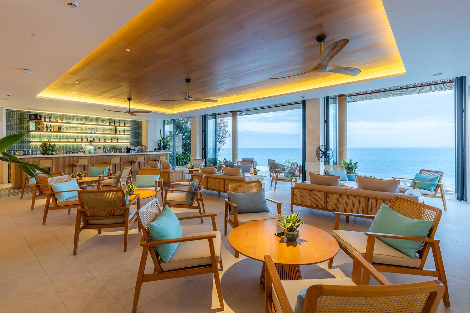 芽莊 Mia 度假村 Mojito's Lounge 木質座席與藍綠靠枕,落地門開向海景