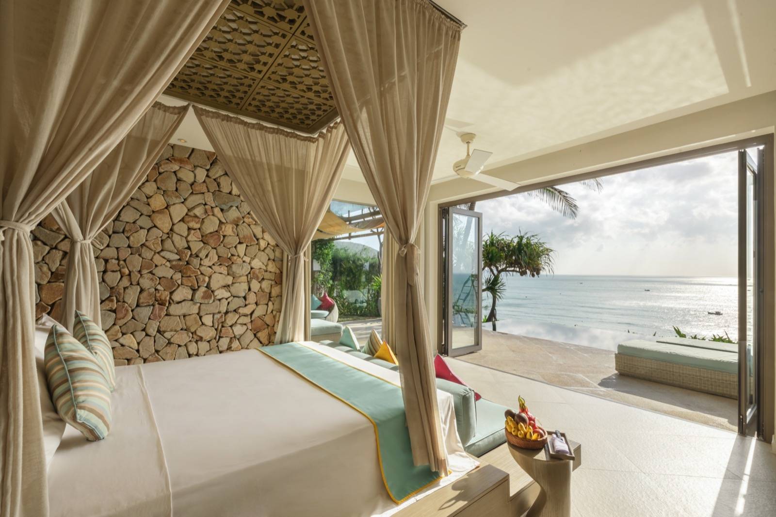 芽莊 Mia 度假村 Cliff Villa 臥室,四柱床與石牆,落地窗看出去是露臺與海景
