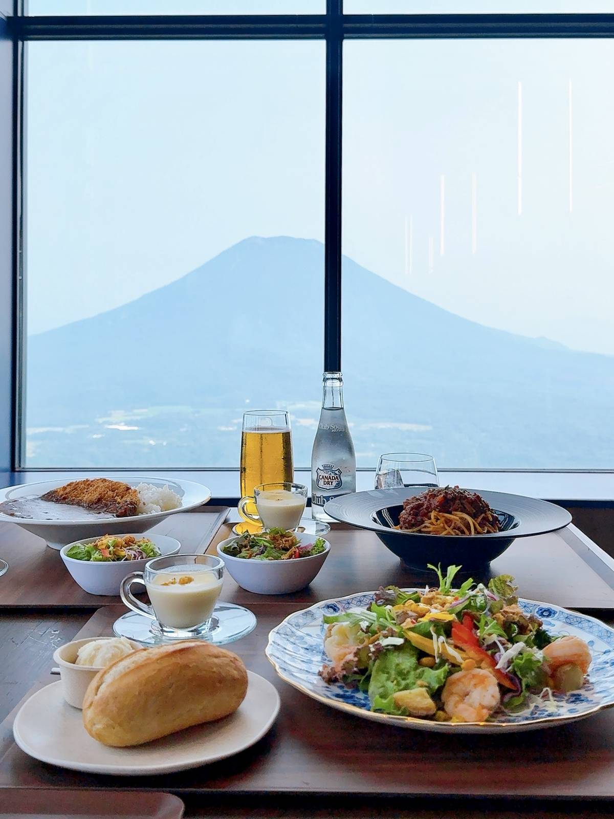 NEST813 窗邊餐桌上的義大利麵、咖哩飯與沙拉及遠方羊蹄山