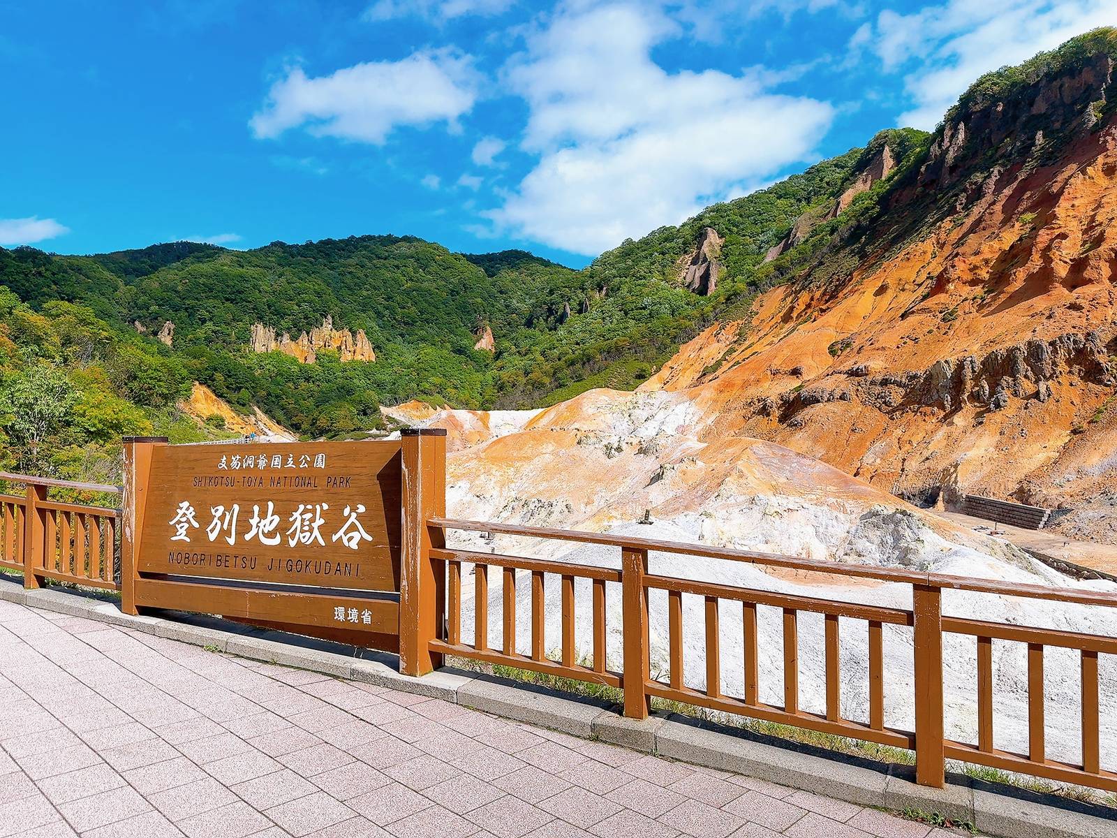 登別地獄谷展望台標示、木欄杆與後方橙褐色火山岩壁
