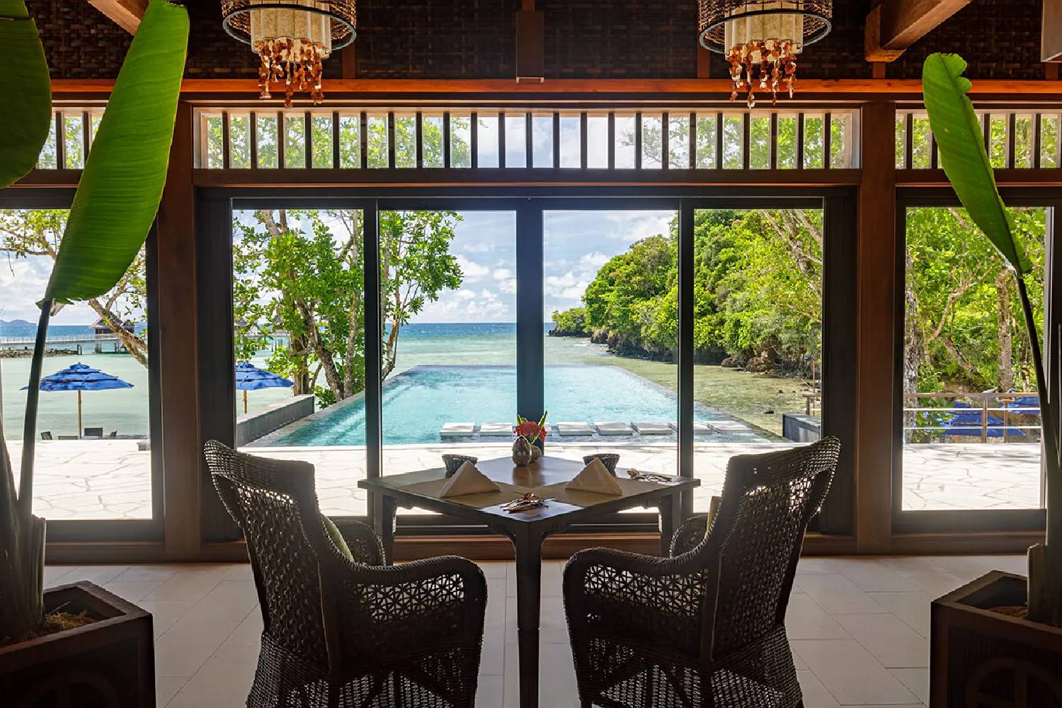 Pristine Dining Room 室內餐桌望向無邊際泳池、沉水躺椅與潟湖