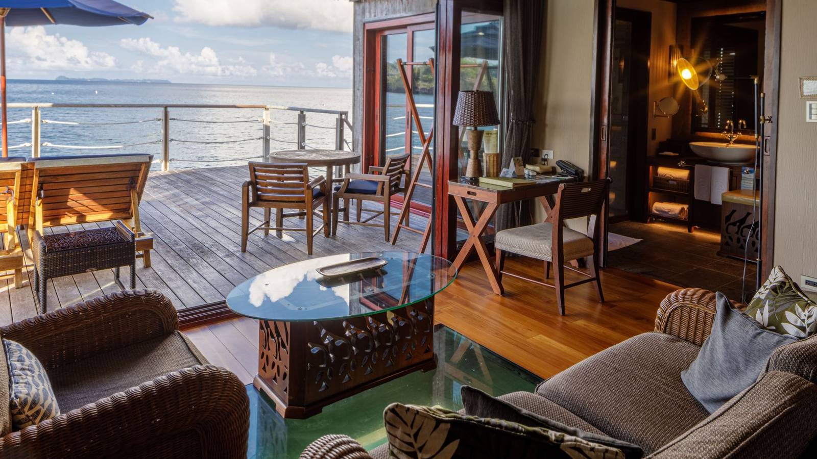 Water Bungalow 室內:藤編沙發、地板玻璃看海、木甲板與藍色遮陽傘