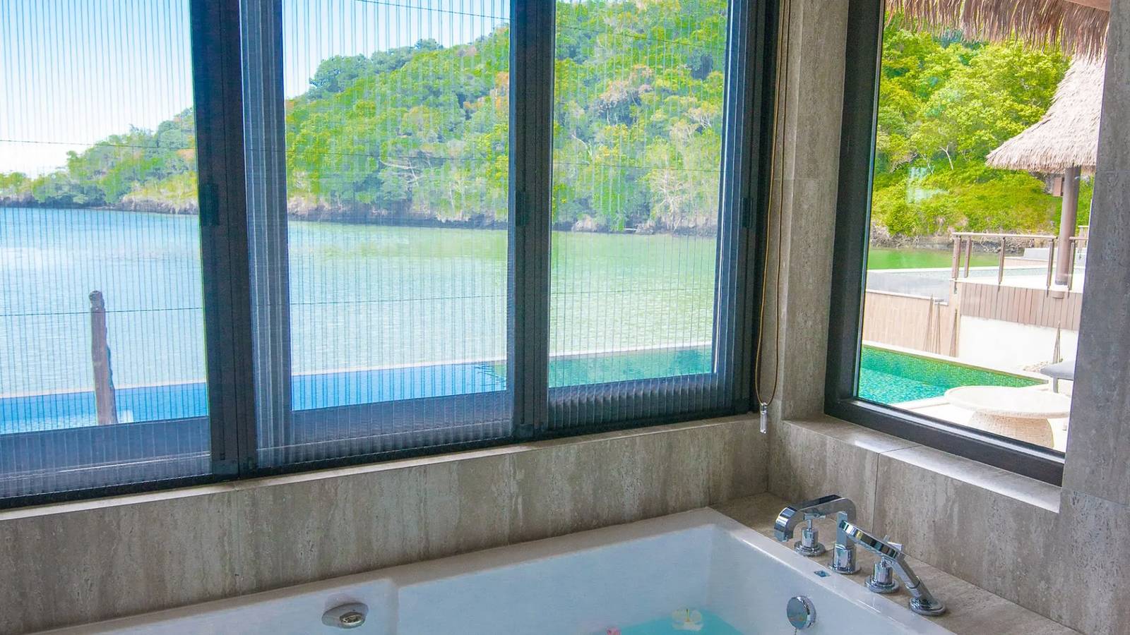 Lagoon View Pool Villa 浴室:白石浴缸、窗外私人泳池與潟湖對岸樹林