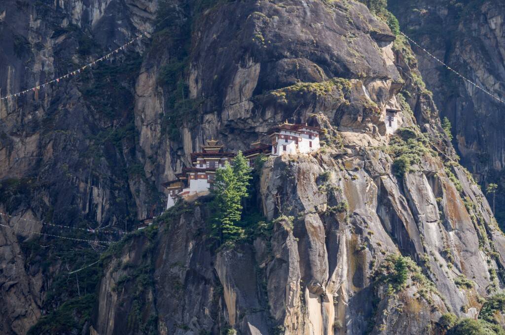 帕羅虎穴寺白牆紅頂寺院鑲嵌在陡峭岩壁上,周圍有經幡