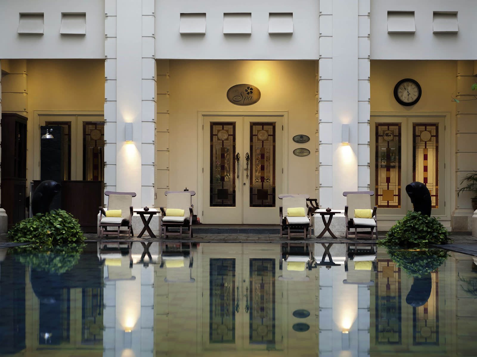 日惹鳳凰翰悅閣酒店倒影水池與黃枕躺椅，門額寫 The Spa 的彩玻雙門