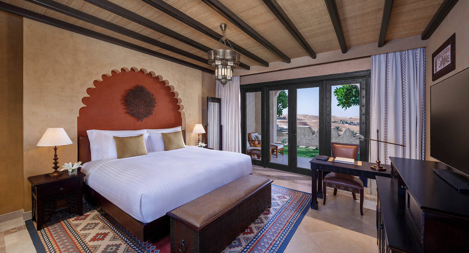 Qasr Al Sarab 度假村客房的紅色拱形床頭與地毯