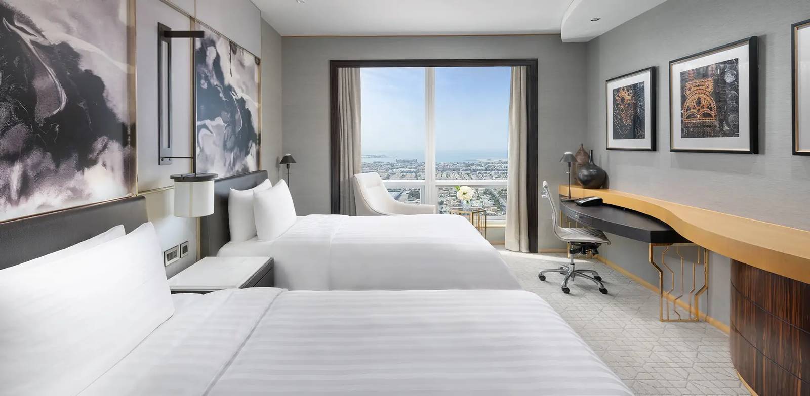 杜拜香格里拉酒店 Deluxe Sea View 客房有兩張單人床、長書桌與落地窗,窗外是市區與海灣