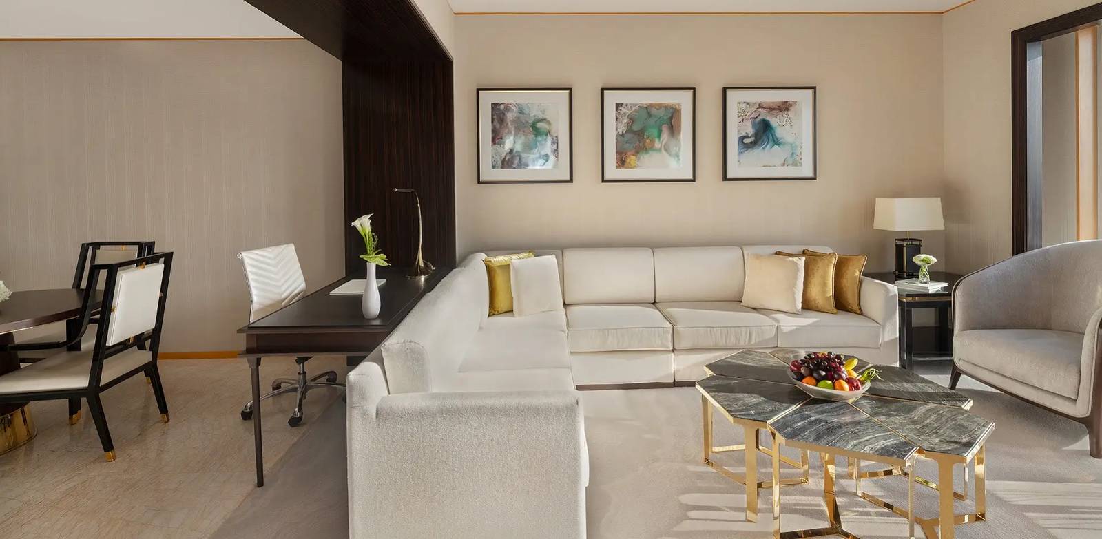 杜拜香格里拉酒店 One Bedroom Suite 客廳有 L 型沙發、六角茶几、後方書桌與左側餐桌