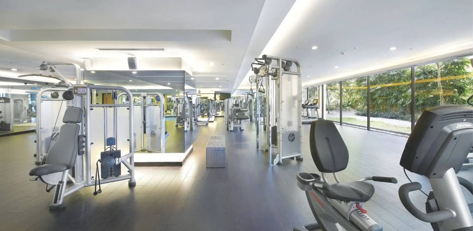 吉隆坡香格里拉 Health Club，跑步機與重量器材面向落地窗，窗外是酒店園林綠意