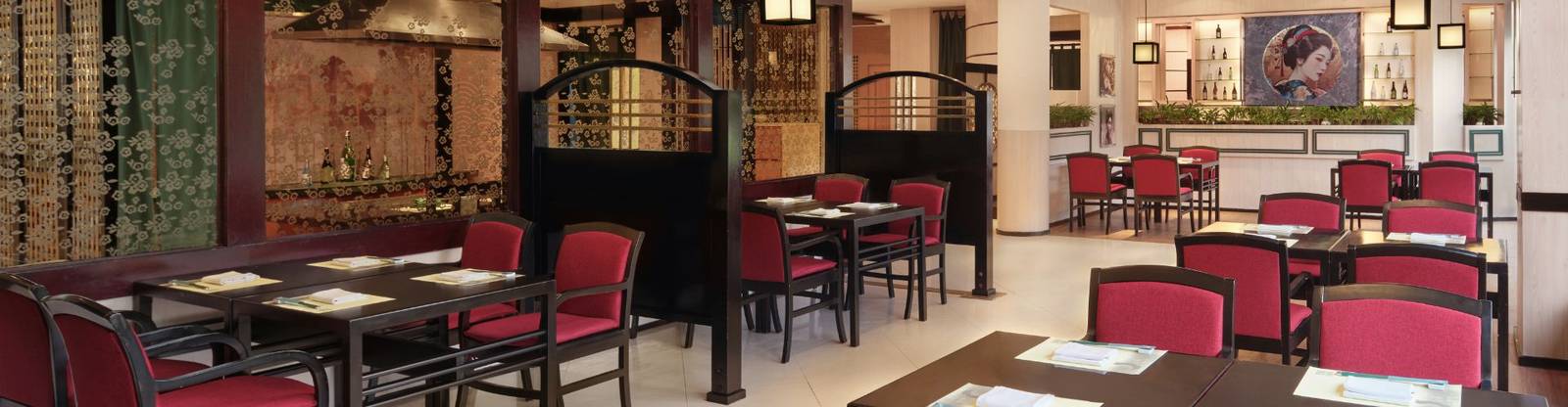 泗水香格里拉酒店 Nishimura 日式餐廳有深色木桌、紅色座椅、方形燈籠與牆上的圓形和風畫像