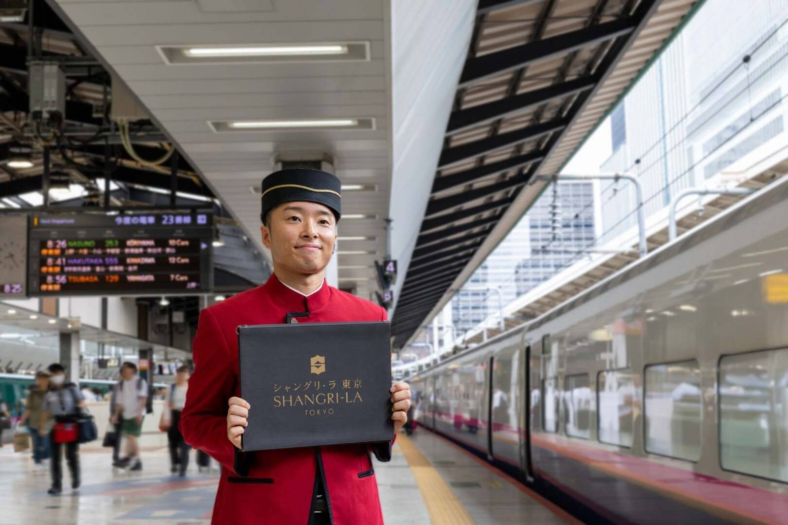東京香格里拉酒店穿紅制服的迎賓人員在新幹線月台手持歡迎牌