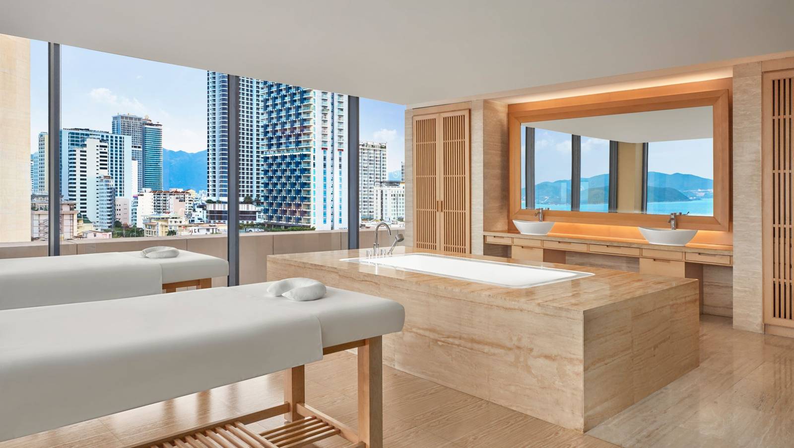芽莊喜來登 Shine Spa 護理室,兩張按摩床、大理石浴缸與落地窗望向市區與海灣