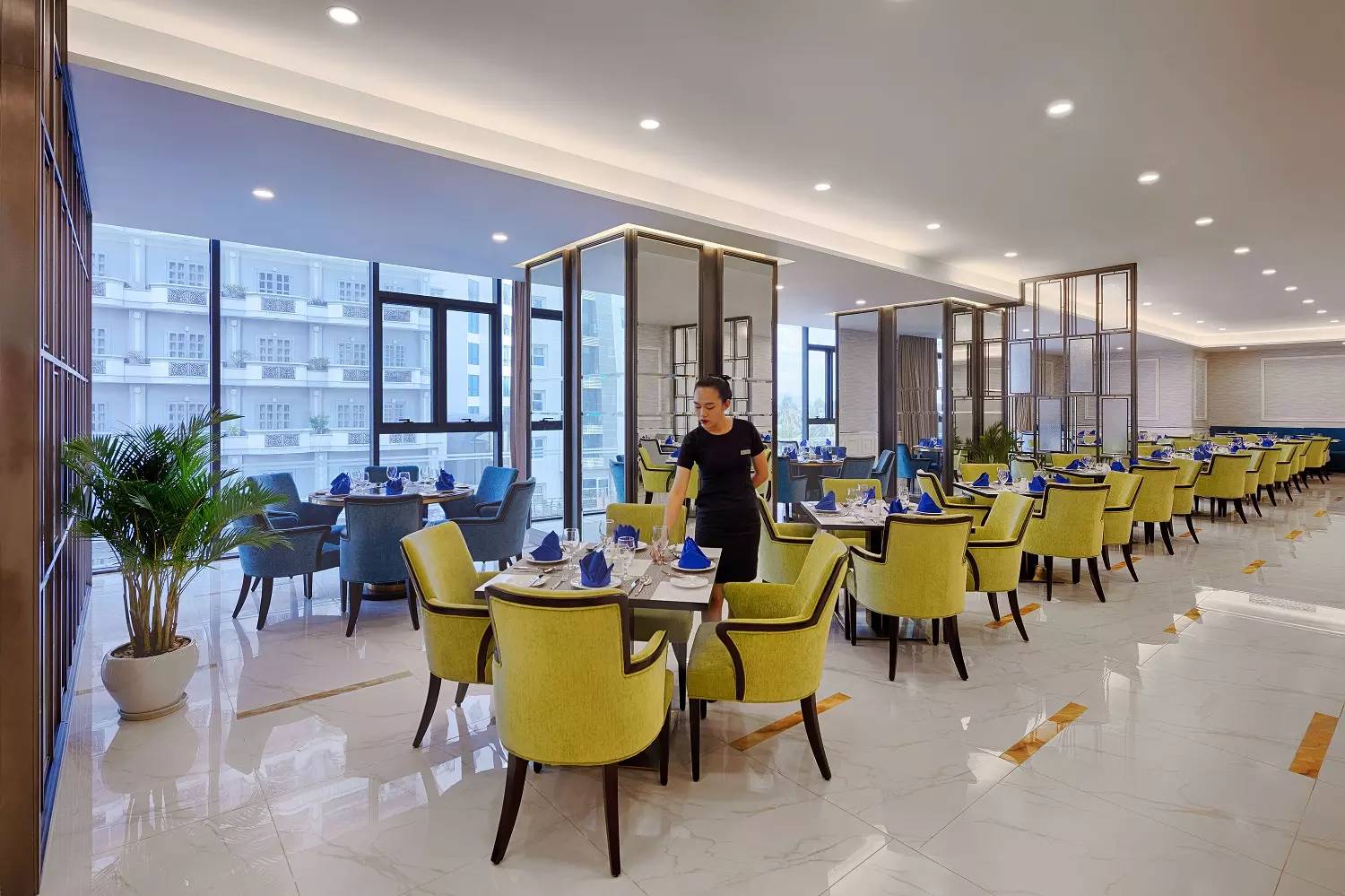 芽莊珍珠海濱酒店 Lagoon 餐廳明亮用餐廳、黃色與藍色座椅與整齊餐桌