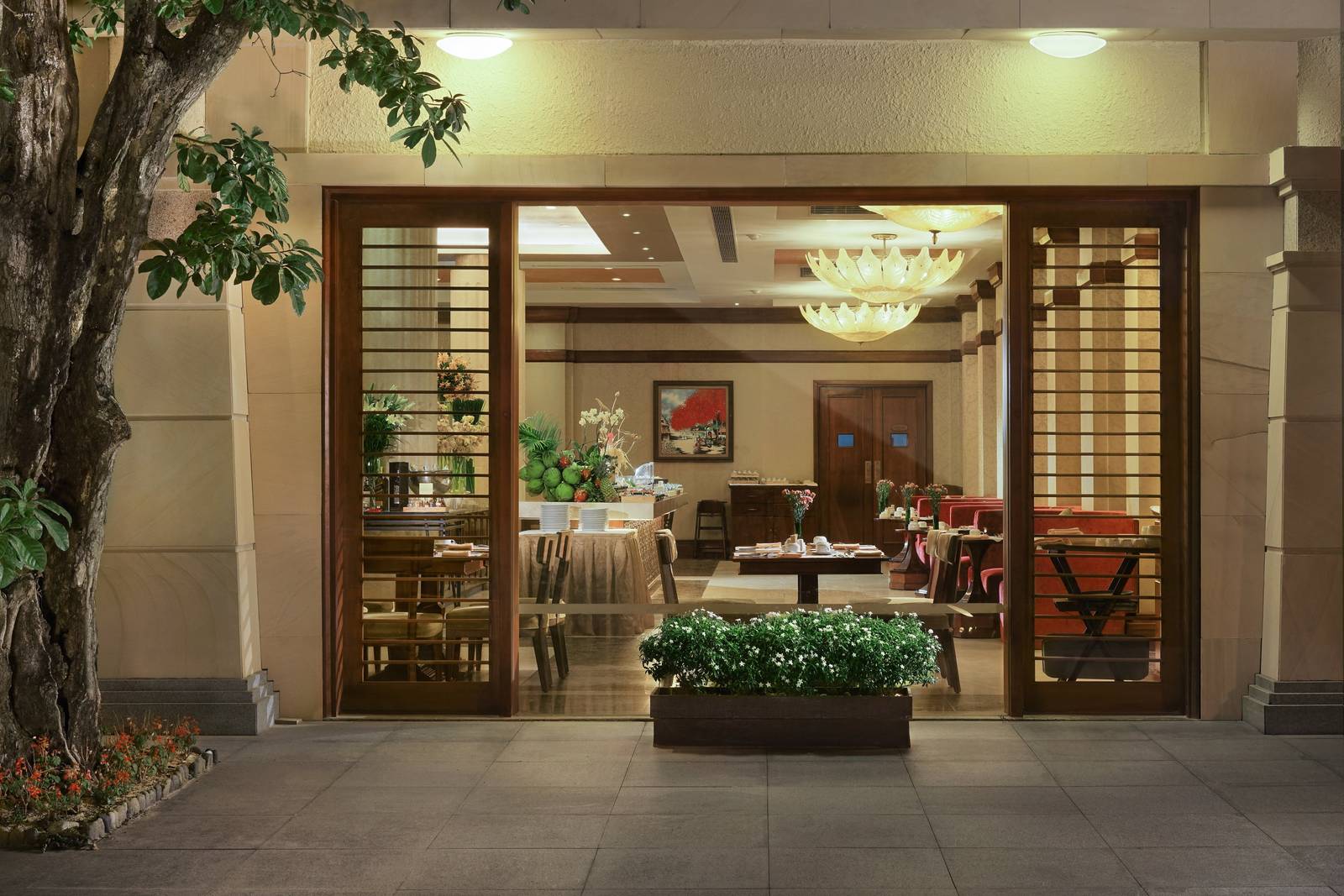 芽莊珍珠奢華度假村夜間餐廳入口，木格柵門內可見蓮花吊燈、餐桌與自助檯