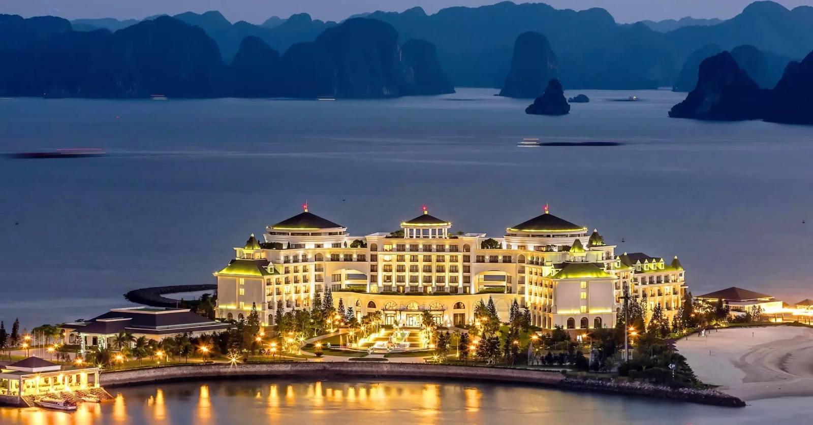 黃昏點燈的下龍灣珍珠水療度假村弓形城堡，水面倒影與遠景峰林