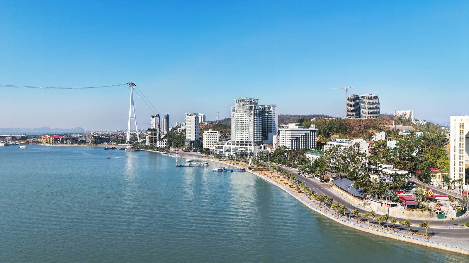 下龍灣白齋海岸日間空拍,沿下龍路高樓、皇后纜車塔與海灣,可見溫德姆傳奇所在水岸