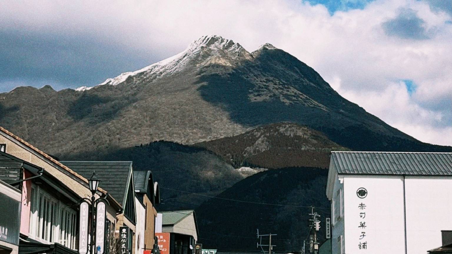 由布岳矗立在由布院街屋後方，山頂點綴白雪