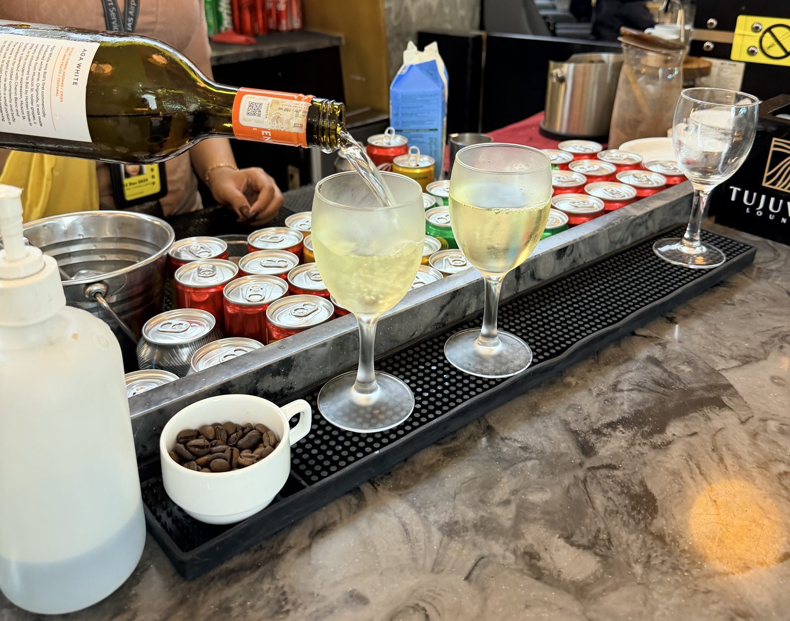 峇里島機場 Tujuwan 貴賓室吧台倒白酒與罐裝飲料