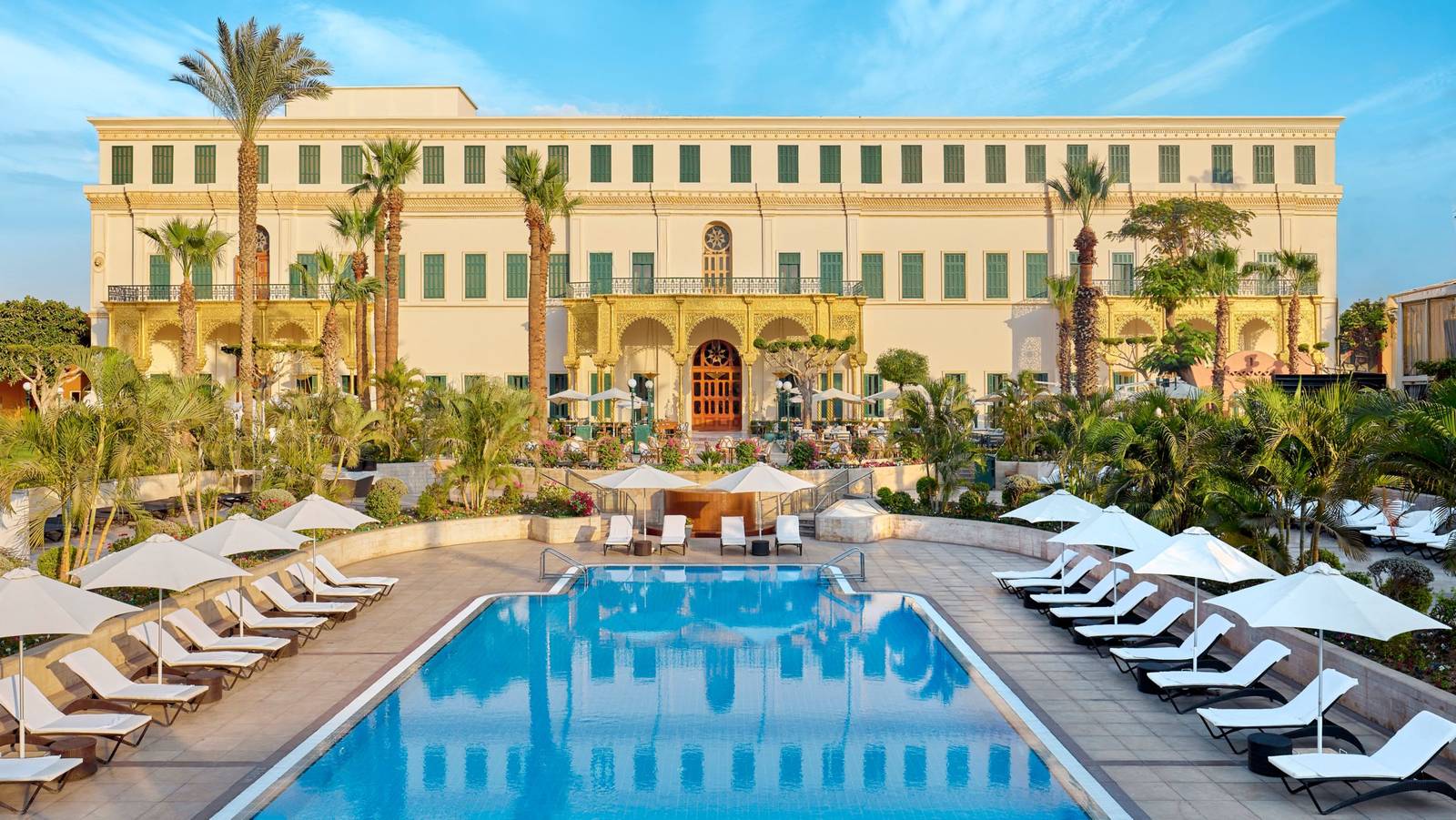 開羅萬豪酒店的戶外泳池，後方是黃色外牆的 Gezirah Palace 與棕櫚樹