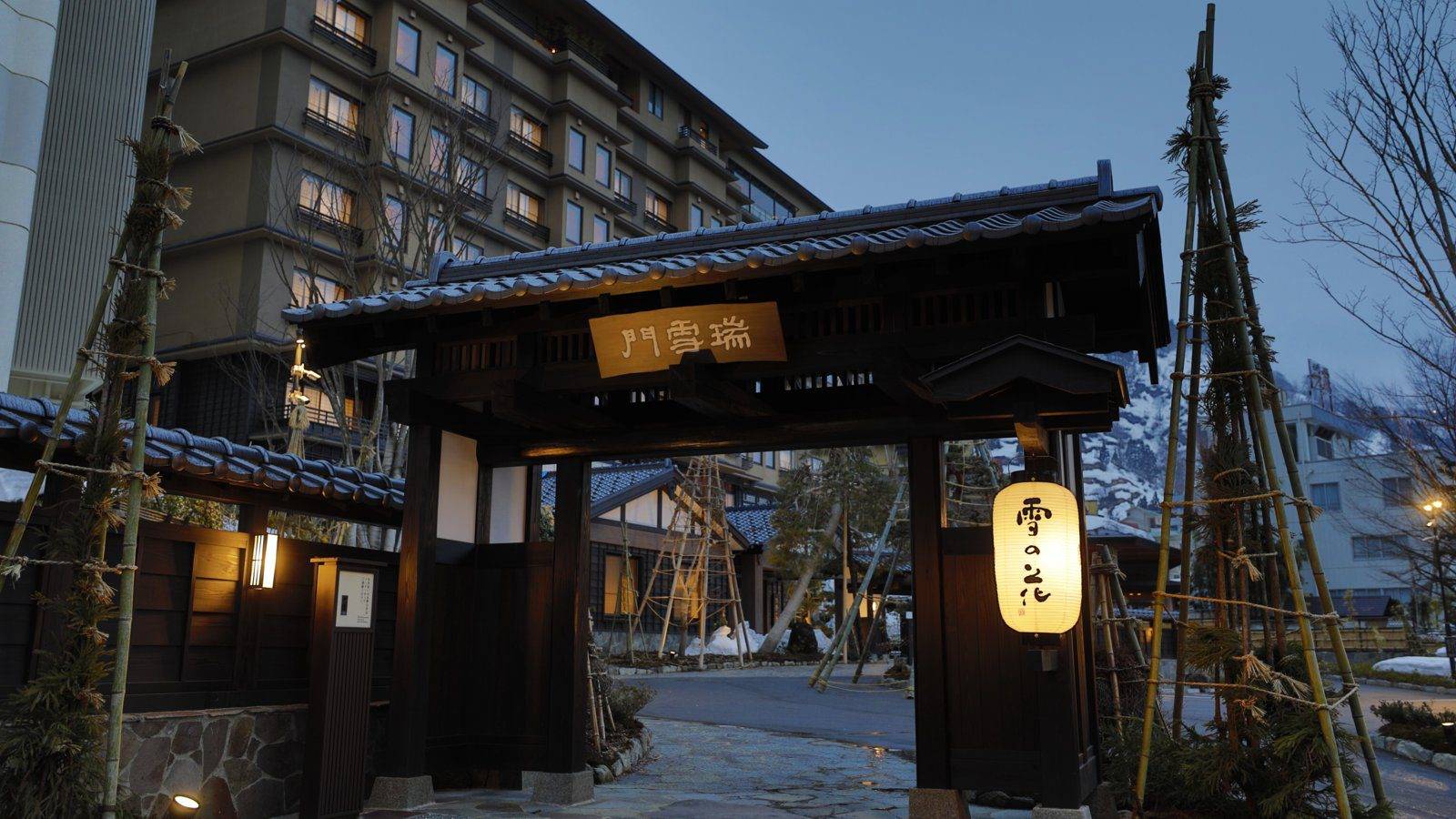 越後湯澤溫泉 湯煙之宿 雪之花 夜間亮燈的門與後方旅館大樓