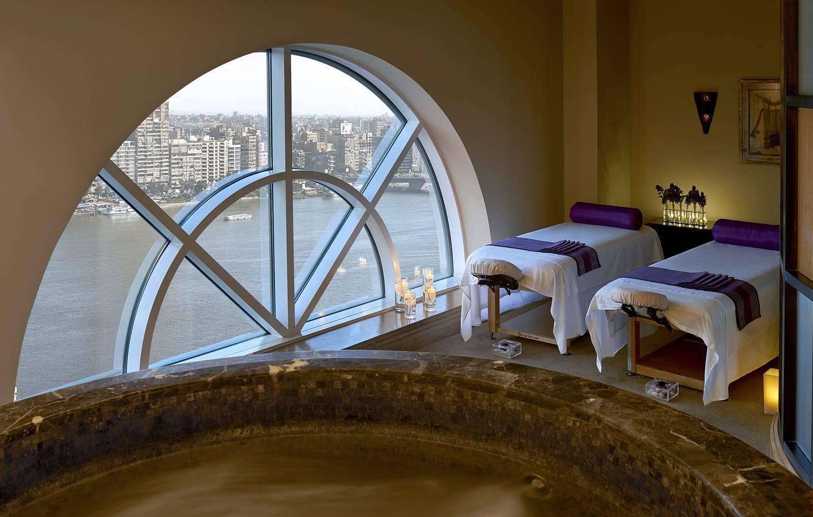 開羅第一居庭四季酒店 Spa 雙人療程室的按摩床與圓弧窗