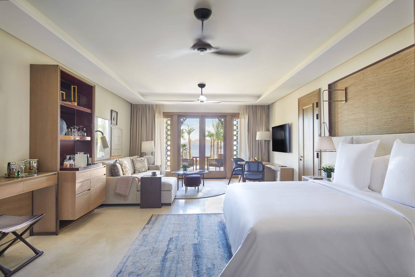 夏姆錫克四季度假酒店 Premier Sea-View Room 的大床、座椅與通往露台的玻璃門