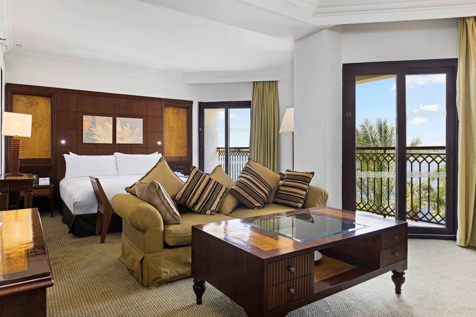 路克索希爾頓度假酒店及水療中心 Nile Suite 的沙發區與床鋪，陽台外是棕櫚樹