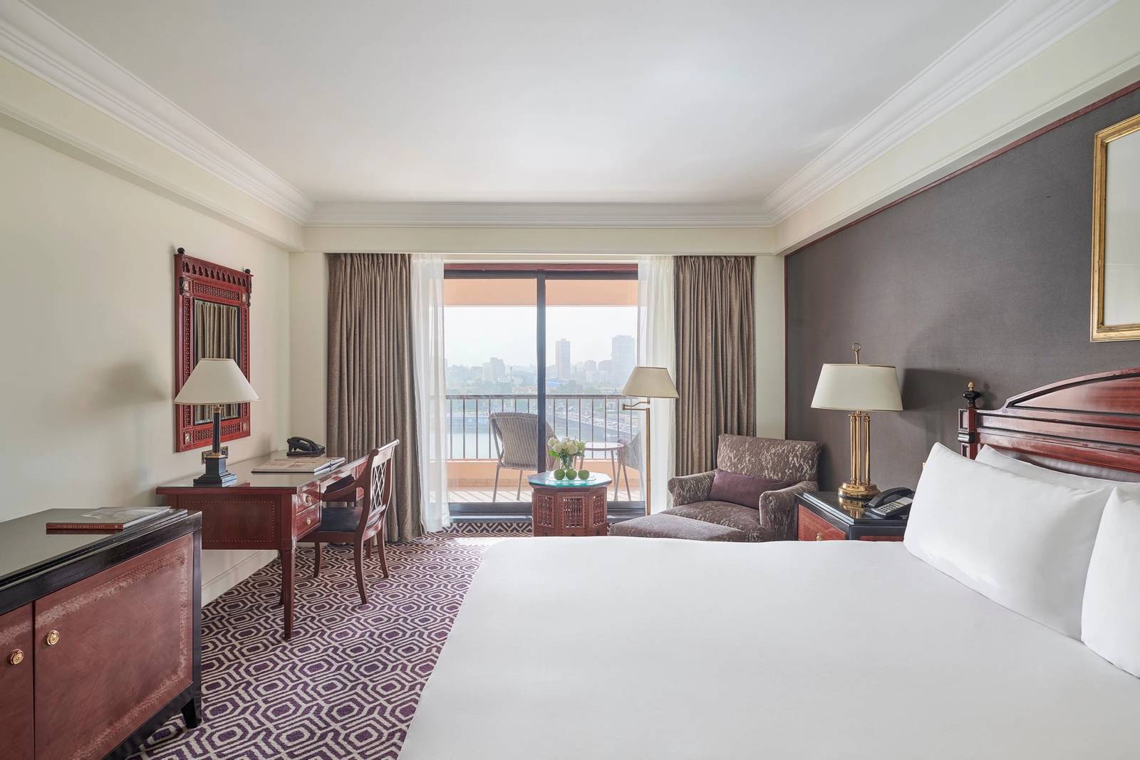 開羅塞米勒米斯洲際酒店 Classic Room 的大床、書桌與通往陽台的落地門