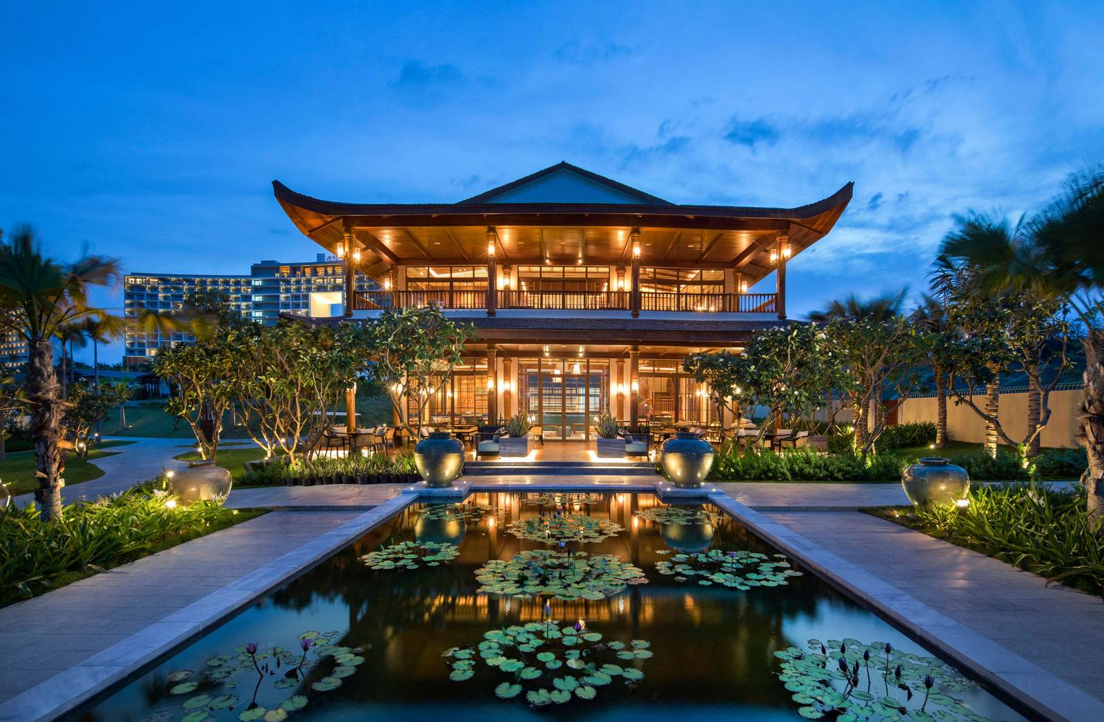 夜裡亮燈的多層屋頂建築與前方蓮花水池