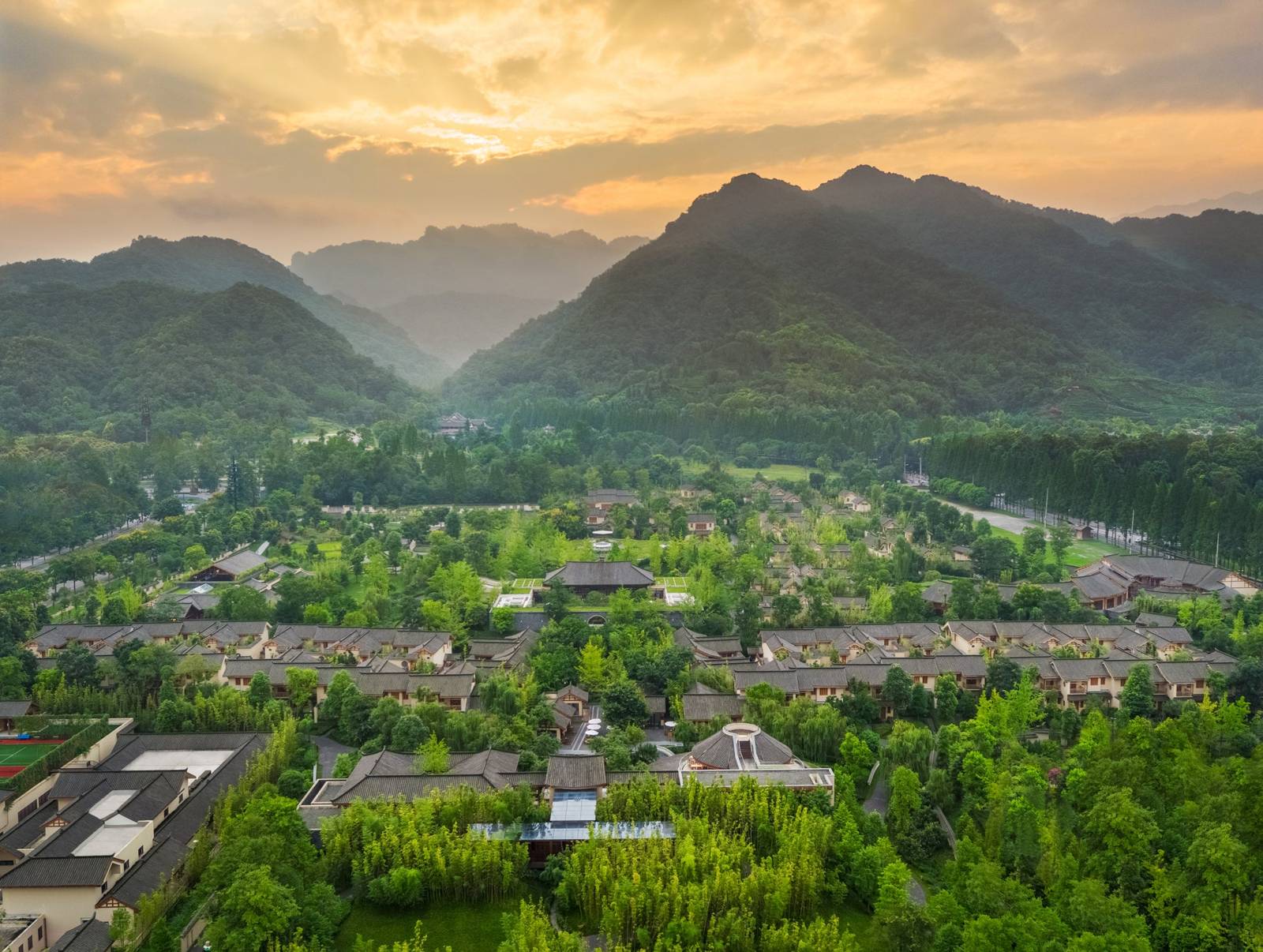 青城山六善酒店園區空拍,背後是青城山群峰與夕陽