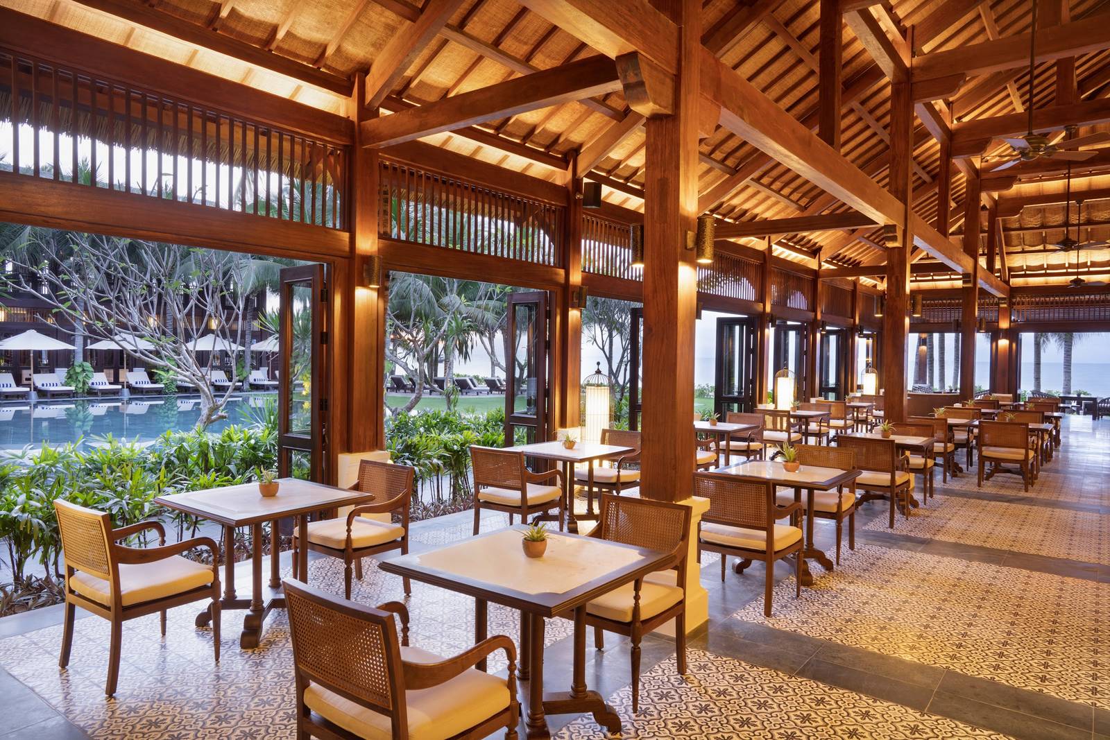 木造屋頂下的開放式餐廳，外面是泳池和陽傘