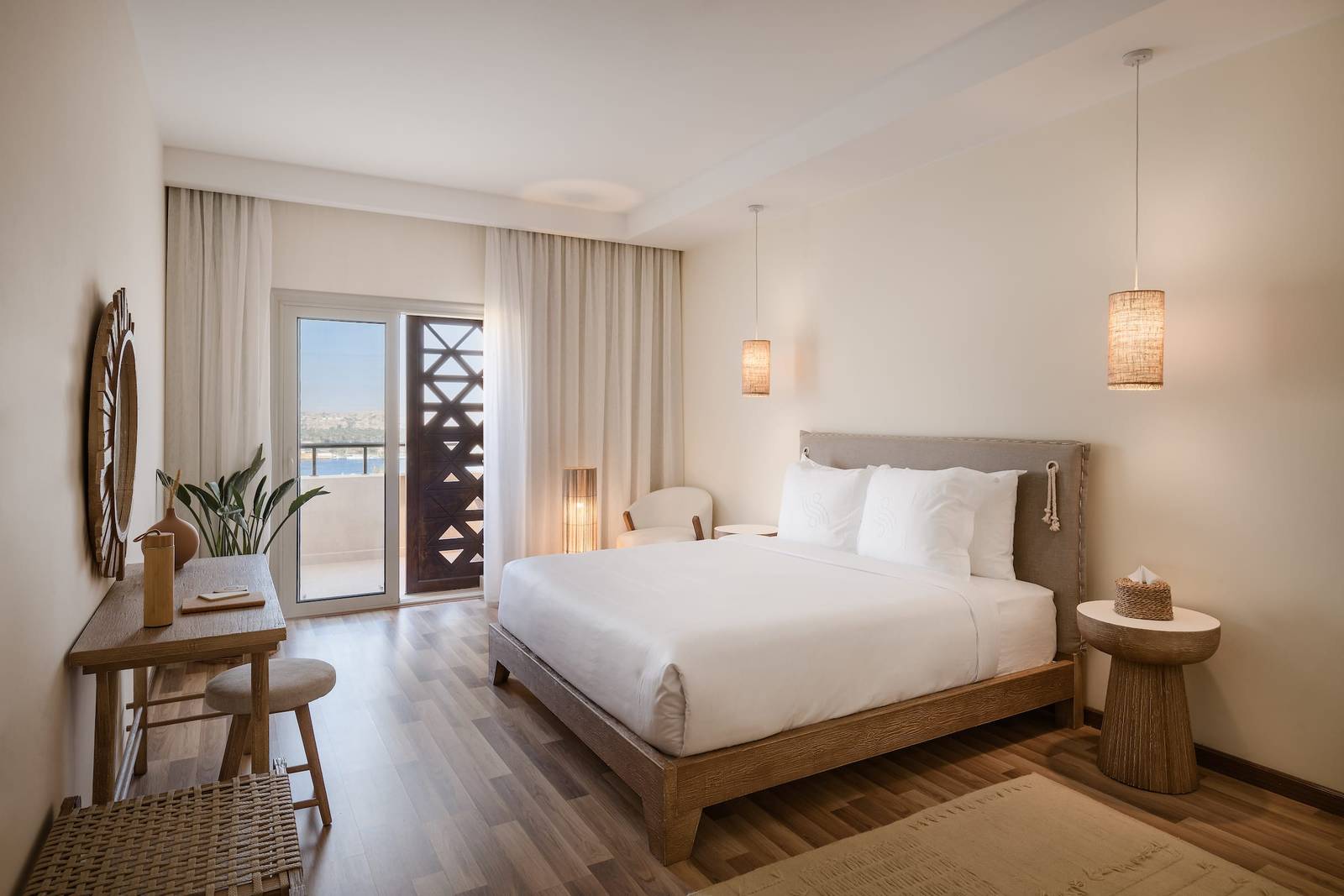 亞斯文 The Zen Wellness 度假村 Deluxe Room 的大床、書桌與通往陽台的落地窗
