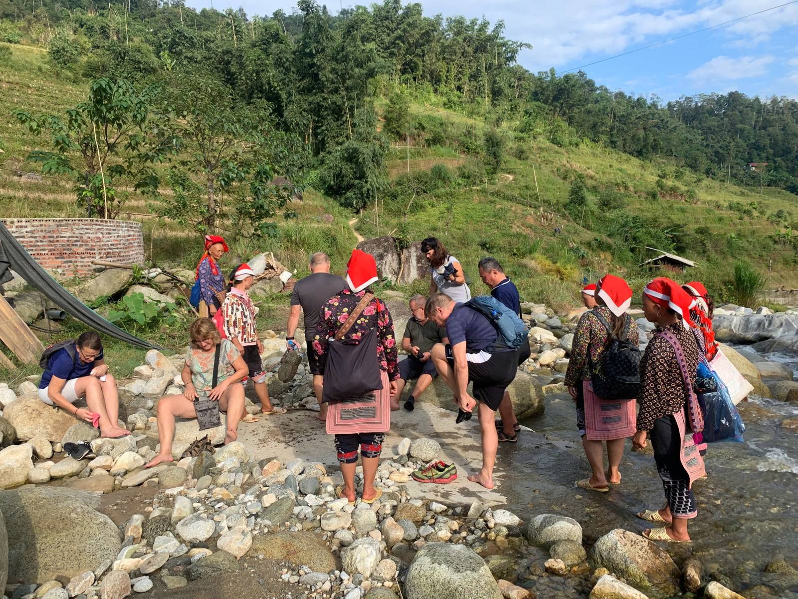 戴紅頭巾的嚮導與一群健行旅客在溪邊石灘